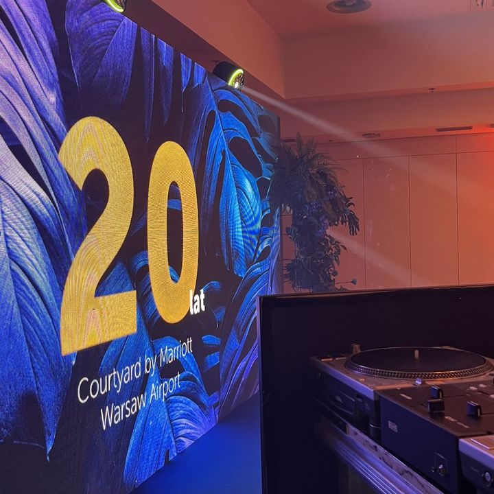 Gramofon przy ekranie LED z jubileuszową grafiką podczas wydarzenia firmowego