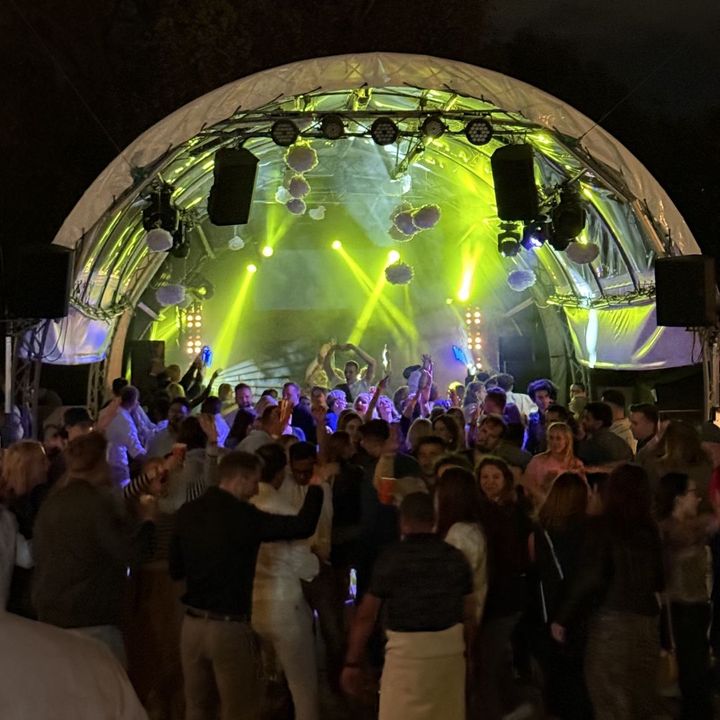 Scena pod kopułą nocą, przed nią tańczący goście na wydarzeniu plenerowym
