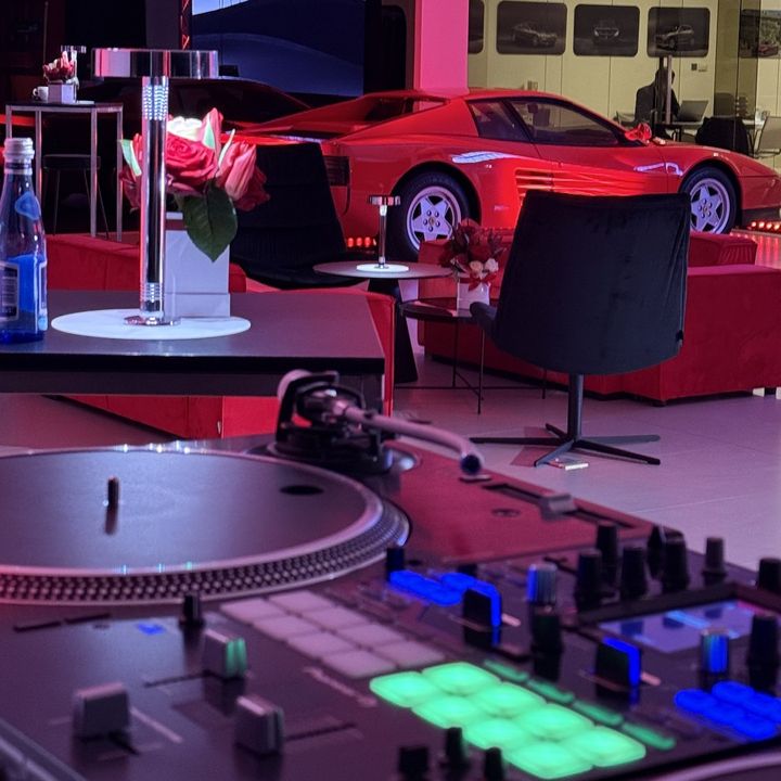 Gramofony w salonie samochodowym, w tle czerwone Ferrari i stoliki z kwiatami